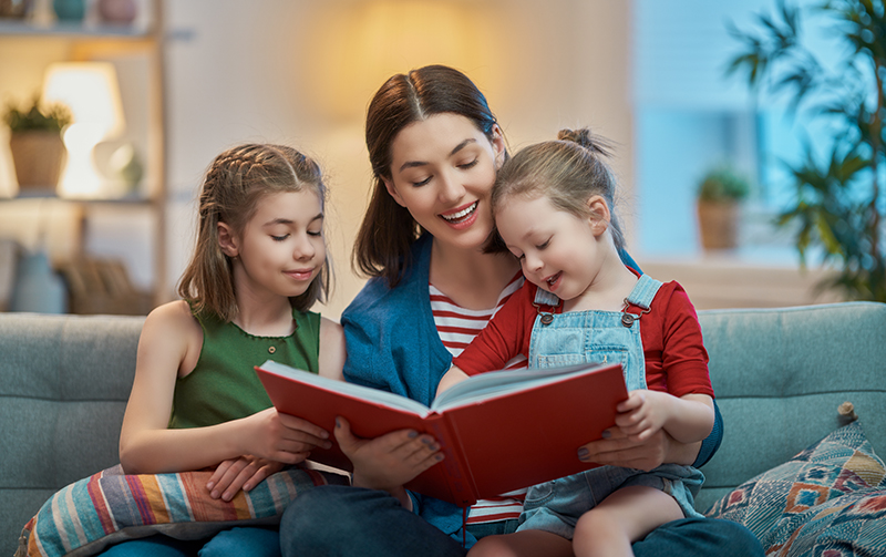 Aunt reading a book with two girls