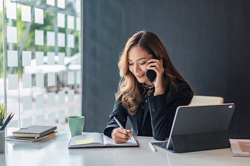 Smiling woman on the phone and taking notes.