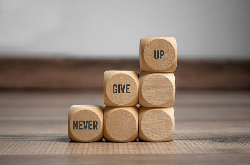 Pyramid made of wooden cubes with message "Never Give Up"