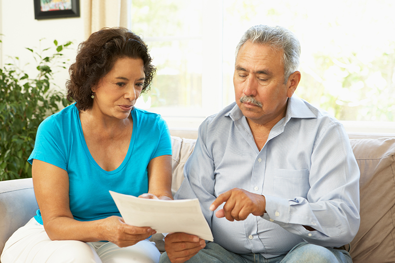 A couple sitting on a couch reading a letter together