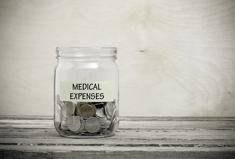 A mason jar labeled "Medical Expenses" filled with quarters