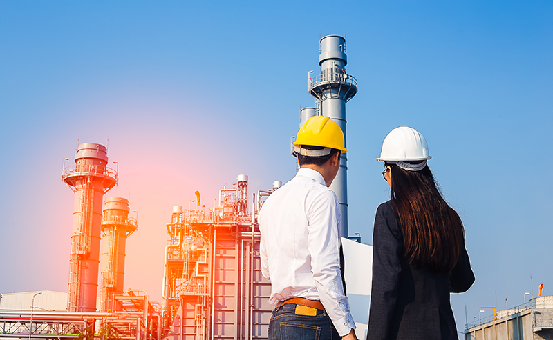 Two people in hardhats looking at a power plant